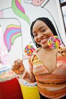 senhora milenar afro-americana na loja de doces com pirulitos. foto