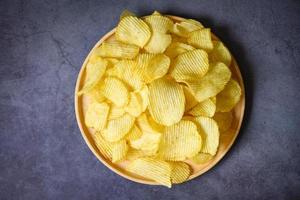 lanche de batatas fritas no prato, batatas fritas crocantes no fundo preto da mesa da cozinha - vista superior foto