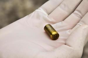 oficiais forenses detém provas físicas que é o cartucho de bala até o nível dos olhos para determinar o tamanho e tipo de munição no assassinato. foto