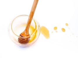 vista superior da vara de mel em frasco de vidro de mel vazio com mancha de mel isolada no fundo branco. foto