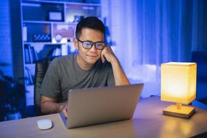 homem freelance trabalhando no laptop em casa à noite. homem freelancer, sorrindo, relaxando depois de terminar o trabalho em casa à noite. trabalho freelance e trabalho em casa conceito. foto