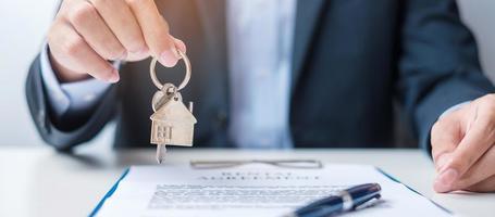 homem segurando a chave de casa durante a assinatura de documentos de contrato em casa. acordo de contrato, imóveis, compra e venda e conceitos de seguros foto