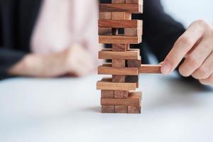 mão de empresária colocando ou puxando o bloco de madeira na torre. conceitos de planejamento de negócios, gerenciamento de riscos, solução e estratégia foto