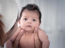 retrato de três semanas bebê recém-nascido asiático australiano ou criança deitada na cama branca e abrindo os olhos. foto