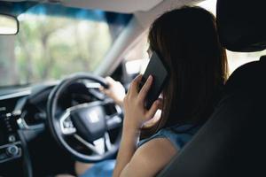 mulher asiática usando telefone celular enquanto dirige mulher está ligando para o seguro ou alguém para ajudar quando o carro quebra ou sofre um acidente. foto