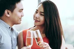 sorriso amante asiático casal homem e mulher mão segurar uma bebida de champanhe e torcer. foto