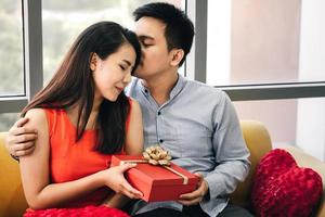 mão de casal de homem segura uma caixa de presente vermelha romântica presente para a namorada. foto