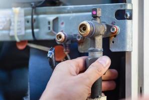 Mãos de homem de reparo de ar condicionado verificando e consertando válvula de serviço de ar condicionado, técnico verifica vazamento de sistema de ar condicionado foto