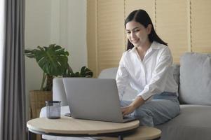 jovem mulher bonita está trabalhando com seu computador em casa. foto