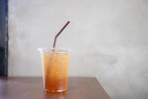 chá gelado de pêssego em copo plástico na mesa de madeira foto