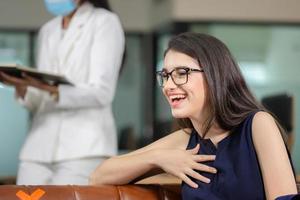 jovem alegre em óculos sentado no sofá no escritório moderno, novo conceito normal foto