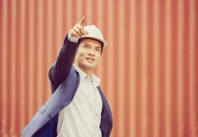 engenheiro homem de capacete apontando para o céu em contêineres de carga foto