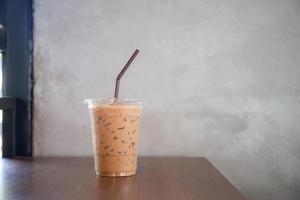 café expresso gelado em copo de plástico na mesa de madeira foto