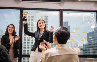 mulher de negócios segurando o troféu de prêmio na sala de reuniões, conceito de equipe de felicidade de sucesso de celebração foto