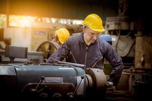 engenharia da indústria vestindo controle uniforme de segurança operando máquina de moagem de torno controlada por computador trabalhando na fábrica da indústria. foto