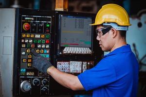 engenharia da indústria vestindo controle uniforme de segurança operando máquina de moagem de torno controlada por computador trabalhando na fábrica da indústria. foto