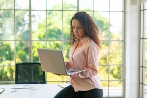 mulher latina trabalhando com laptop na área de trabalho foto