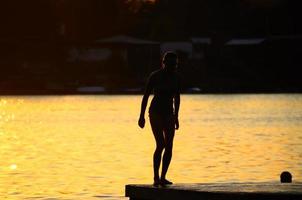 mulher de biquíni no cais à beira do lago foto