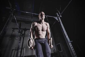 homem de exercício muscular fazendo treino de cross fit no ginásio em anéis de ginástica foto