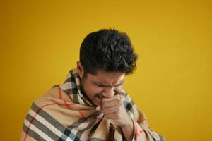 jovem doente tosse e espirra contra backgorund amarelo foto