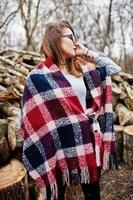 garota jovem hippie usar cobertor e óculos contra tocos de madeira na madeira. foto