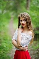 retrato de menina bonita com lábios vermelhos no jardim de flor de primavera, use vestido vermelho e blusa branca. foto