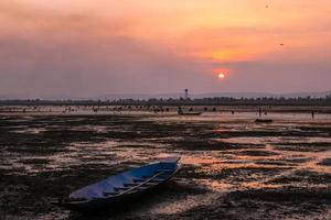 nascer do sol com terra árida e barco de pesca foto