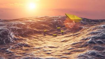 pôr do sol com onda de combate de barco de papel no oceano, liderança e conceito de negócios foto
