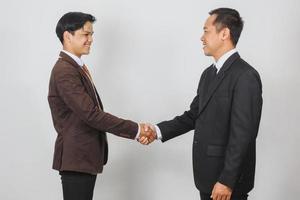 dois empresários asiáticos de terno e gravata olhando um ao outro fazendo aperto de mão foto