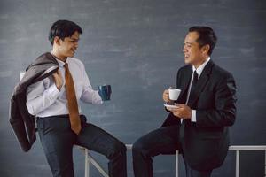 dois empresários asiáticos conversando enquanto seguram café no intervalo foto
