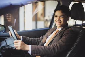 empresário asiático está dirigindo um carro enquanto sorri para a câmera foto