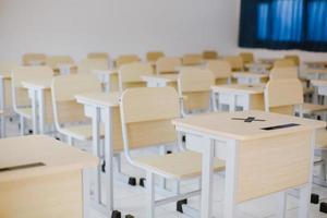 muitas mesas e cadeiras de madeira bem dispostas em sala de aula vazia