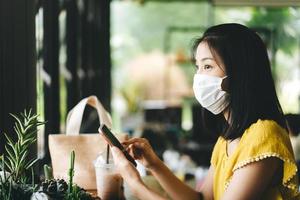 mulher asiática adulta relaxa no restaurante no fim de semana com máscara para novo normal após covid foto