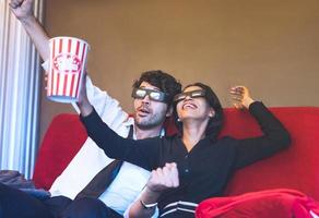 casal lindo feliz sentado no sofá vermelho no cinema. foto