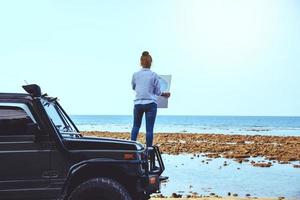 mulher asiática viajar natureza. viajar relaxar. fique no carro e na alça do mapa na praia. no verão. Tailândia foto