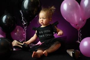 dia da festa de aniversário da menina do primeiro ano. balões e férias dentro de casa. aniversário da criança. menina bonita em seu primeiro vestido preto foto