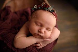 linda garota recém-nascida dormindo em uma banheira em um fundo de madeira. foto