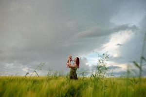 uma mãe com ternura segura seu filho de três meses em seus braços em um campo de trigo. foto