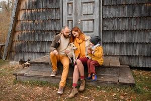 uma família feliz senta-se nos degraus em frente à entrada da casa. foto