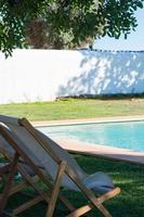 bela piscina e área verde com espreguiçadeiras para descansar. dia ensolarado, conceito relaxar. algarve, portugal foto