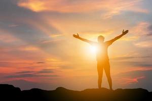 silhueta de felicidade de sucesso de celebração de homem em um fundo de pôr do sol do céu noturno no topo da montanha, esporte e conceito de vida ativa com traçado de recorte foto