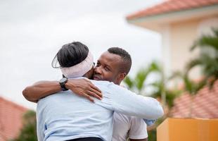 homem afro-americano alegre abraçando namorada em sua nova casa, família de felicidade e conceitos de dia em movimento foto
