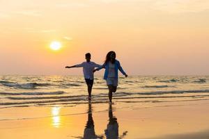 mãe e filho correndo ao longo de uma praia, pai de família feliz asiático com menino criança correndo e se divertindo na praia foto