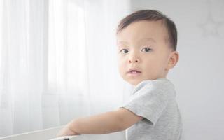 retrato de menino feliz em pé na cama e olhando para a câmera, crianças brincando e conceito de felicidade foto