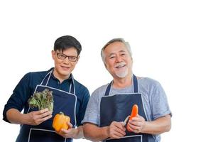alegre pai asiático sênior e filho de meia idade cozinhando juntos na cozinha, pai asiático sênior e filho com traçado de recorte em fundo branco, conceitos de família asiática de felicidade foto