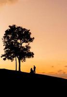 silhueta de pai mãe e filha brincando ao pôr do sol na noite, conceito de família feliz. foto