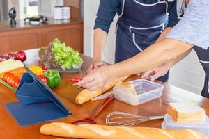 alegre pai asiático sênior e filho de meia idade cozinhando juntos na cozinha, conceitos de família asiática de felicidade foto