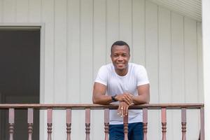 alegre homem afro-americano na varanda de madeira e olhando para a câmera foto