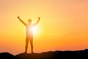 silhueta de felicidade de sucesso de celebração de homem em um fundo de pôr do sol do céu noturno no topo da montanha, esporte e conceito de vida ativa com traçado de recorte foto