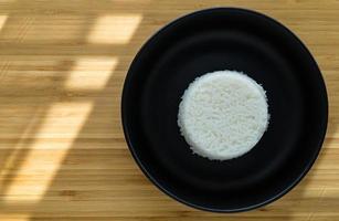 estilo tailandês cozinhar arroz a vapor colocar na chapa preta sobre fundo de madeira com espaço de cópia. ângulo de visão superior. foto